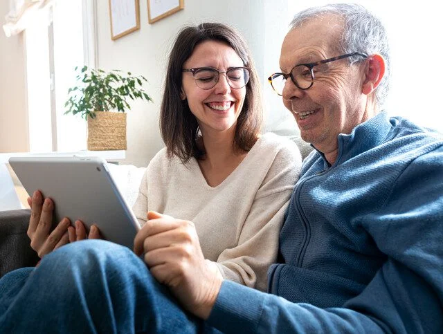 Older adult man browses senior living communities with adult daughter.