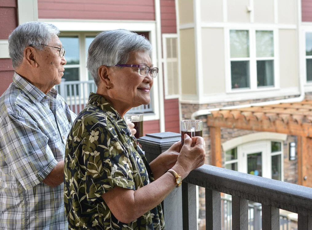 senior couple enjoys coffee on the balcony at Greenfields of Geneva senior living community
