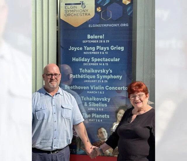 senior couple poses for a photo in front of an award