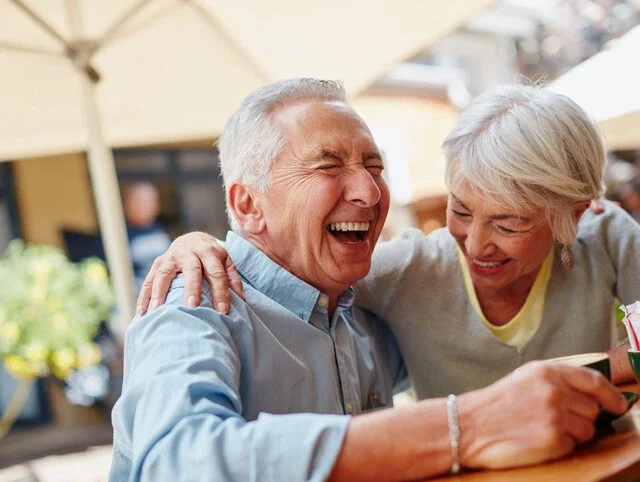 senior couple laughing and enjoying a meal outdoors