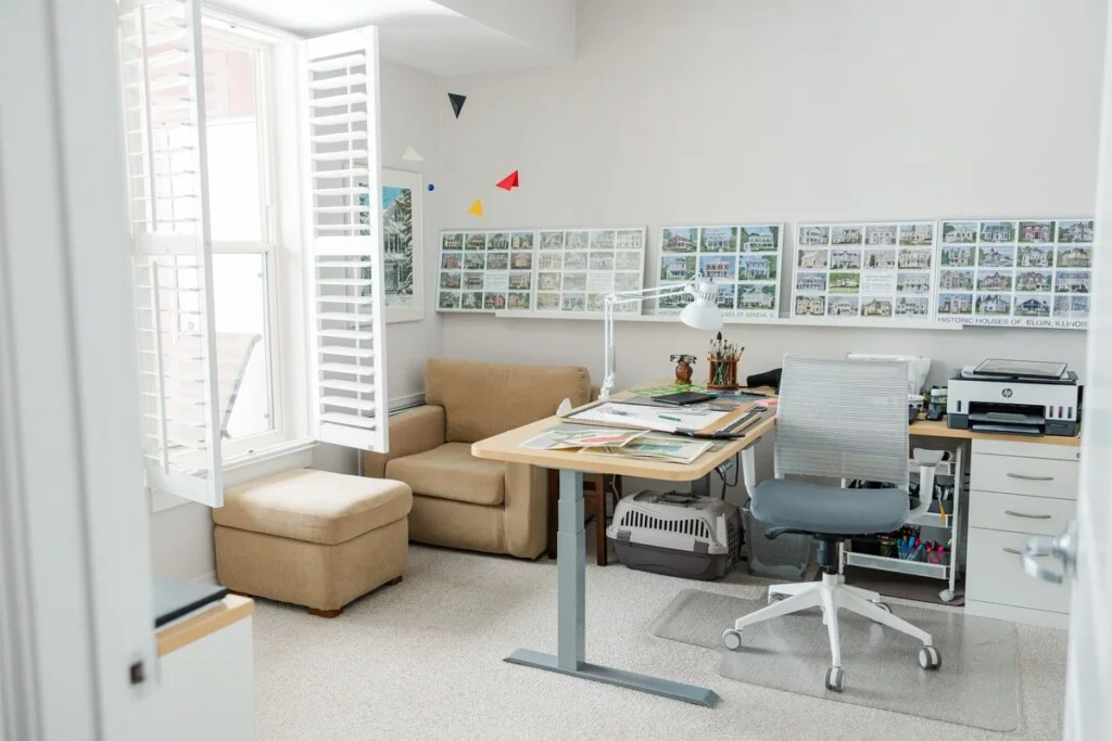 A room in a GreenFields of Geneva apartment set up as an art studio, with a drafting desk, art supplies, and framed prints.