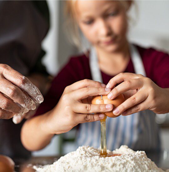 girl breaking an egg into flour