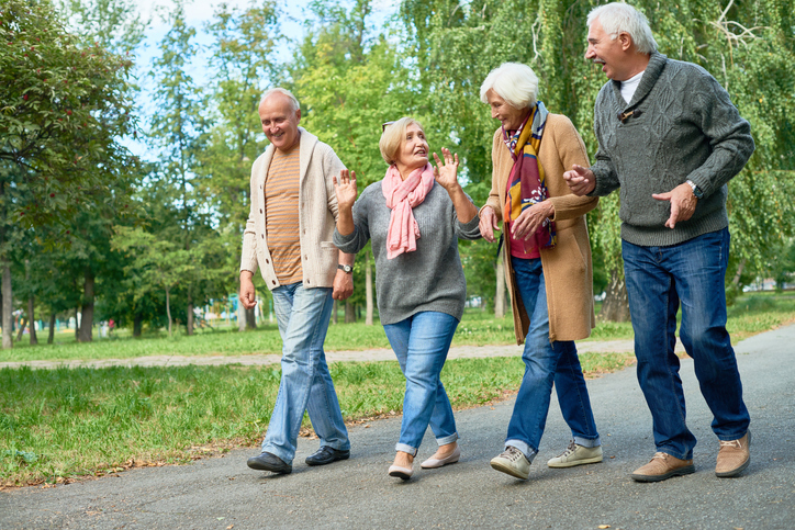 Four seniors walking through a park