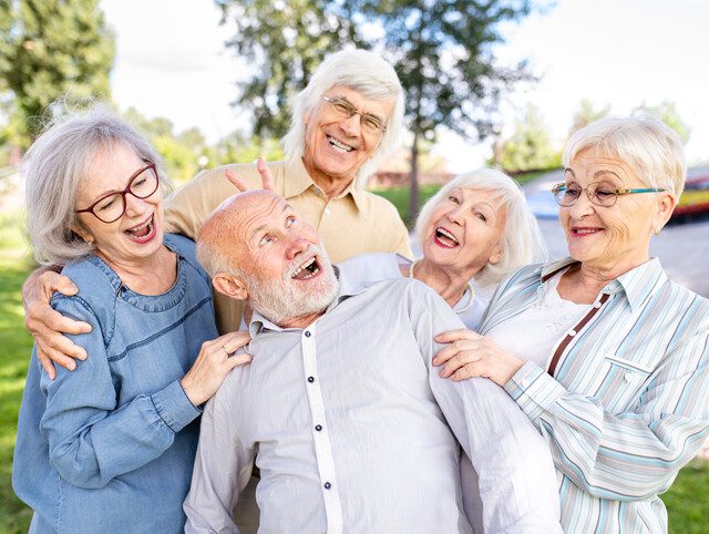 A group of seniors laughing while spending time together outdoors