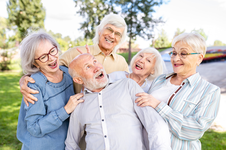 A group of seniors laughing while spending time together outdoors