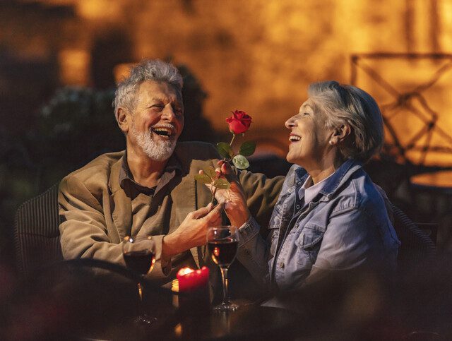 A senior man giving a senior woman a rose on a date