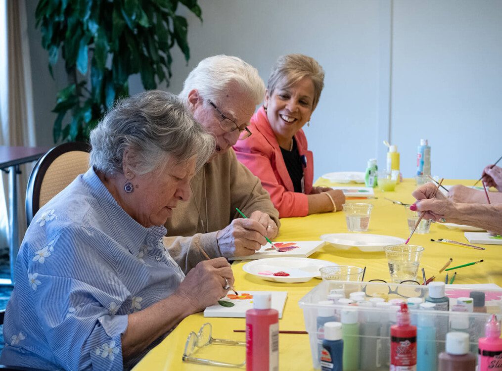 group of senior women smile and create crafts at their senior living community