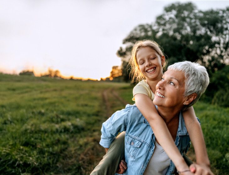 Grandmother carrying her granddaughter on back outdoors
